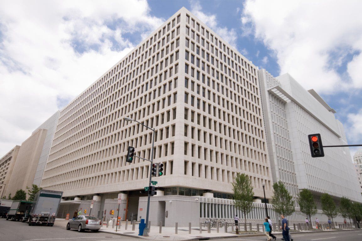 Modern office building with grid facade on an overcast day, traffic light in the foreground.