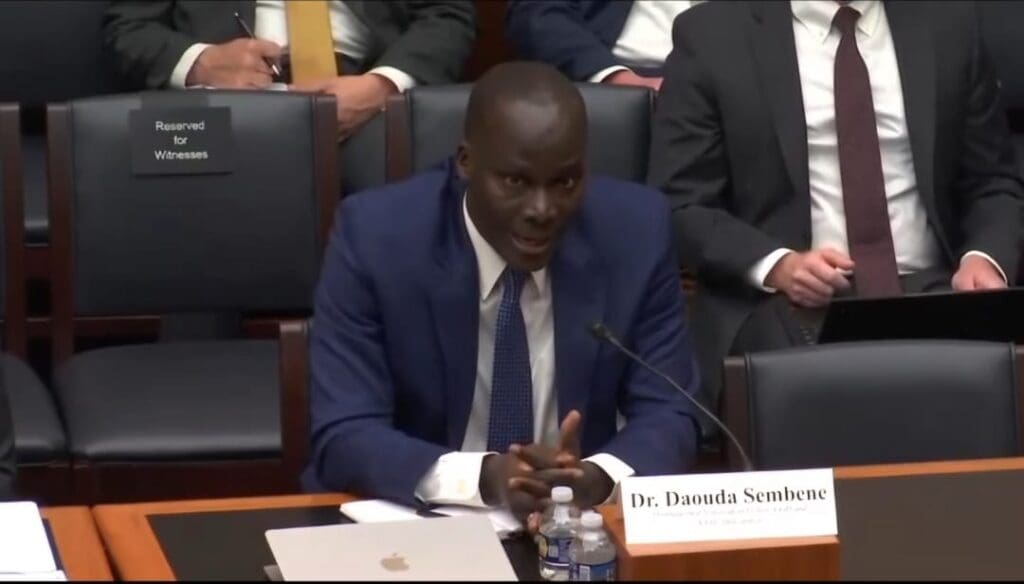 Man in a suit speaking at a hearing.