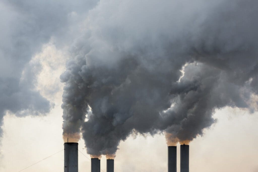 Industrial smokestacks emitting thick smoke into the sky.