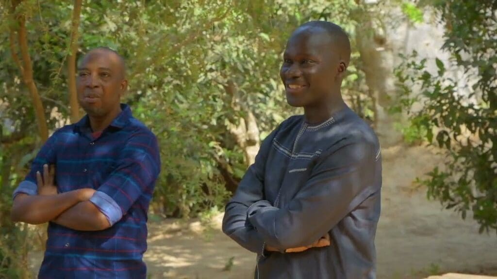 Two men standing outdoors smiling.