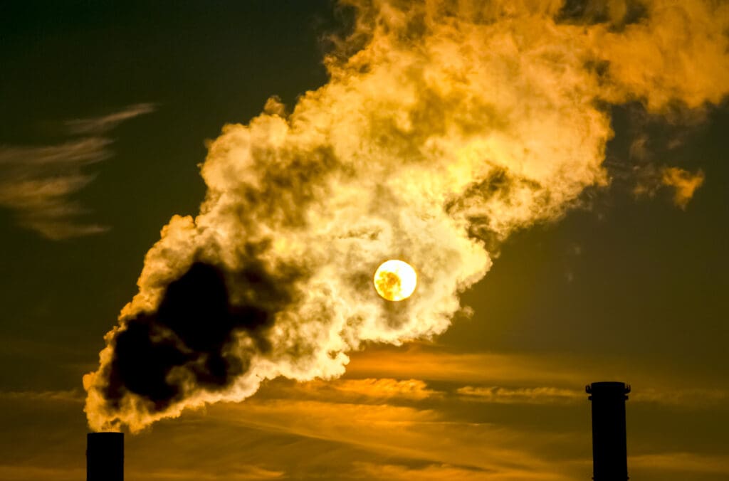 Sunset behind industrial smoke stacks.