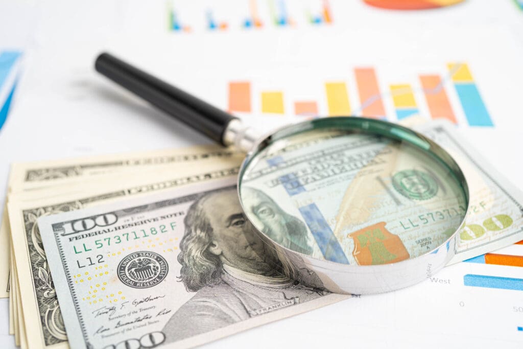 Magnifying glass on money and charts.