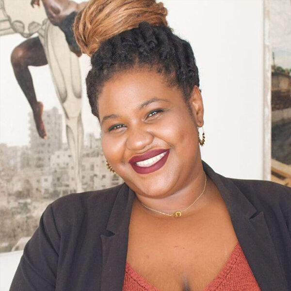 Smiling woman with dreadlocks in a blazer.