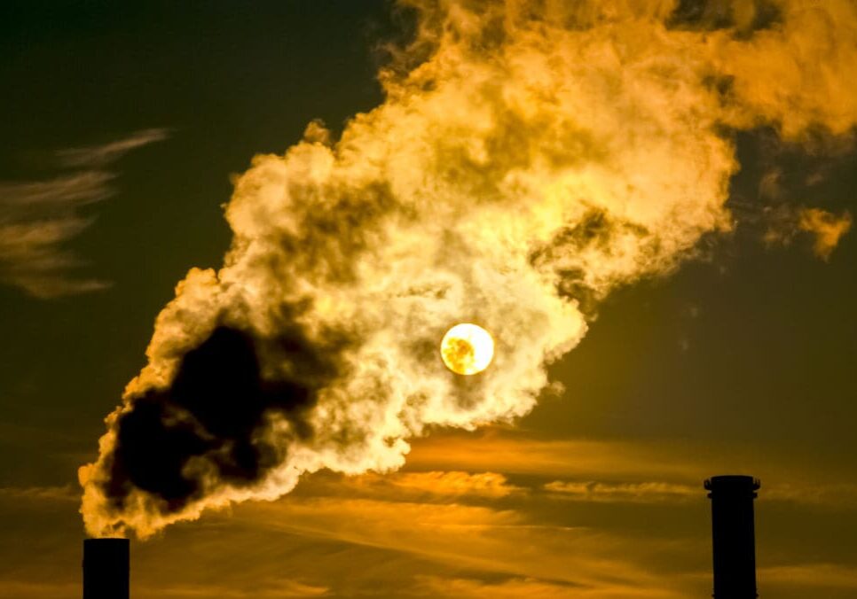 Sunset behind industrial smoke stacks.