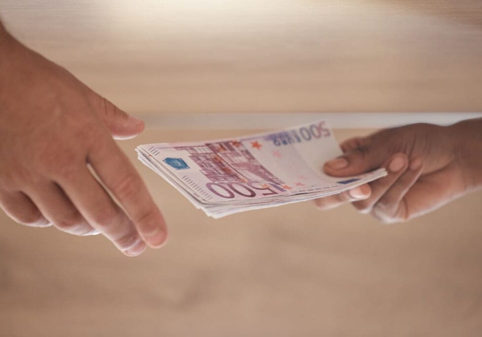 Bribe, hands and cash money exchange for a business bribery or illegal partnership offer. Closeup of businessmen with a dollar finance deal for money laundering, corruption or loan payment in office.