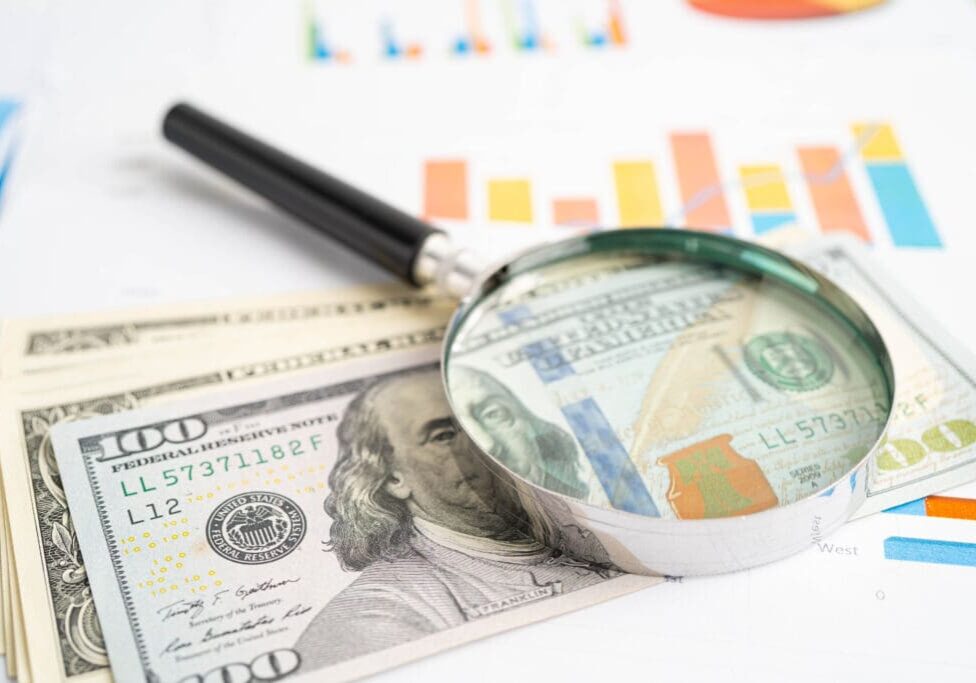 Magnifying glass on money and charts.