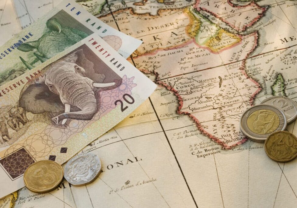 South African rand notes and coins on map
