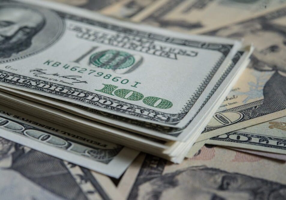 A stack of us dollar bills on a surface.