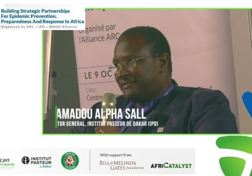 A man at a conference with a name tag, "amadou alpha sall," indicating his position as the director general of the institut pasteur de dakar.