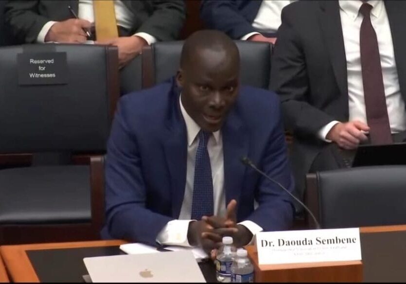 Man in a suit speaking at a hearing.