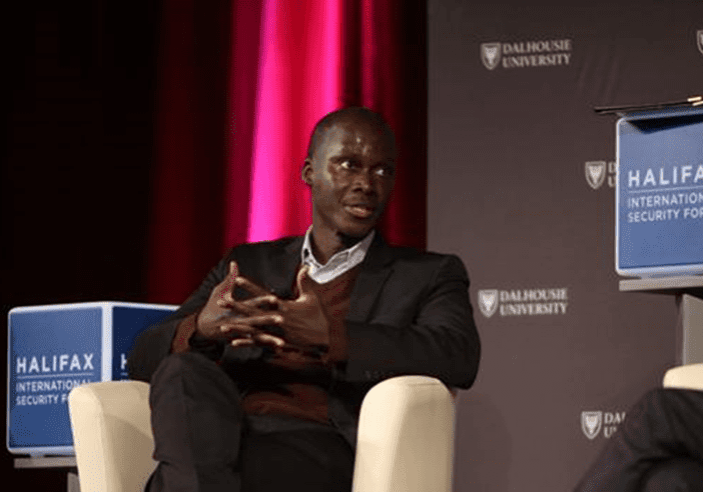 Man speaking at a panel during the halifax international security forum with dalhousie university branding in the background.