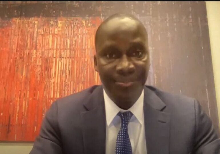 Man in suit smiling, in front of art.