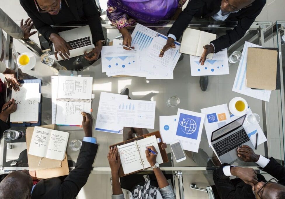 A group of people sitting around a table with papers.