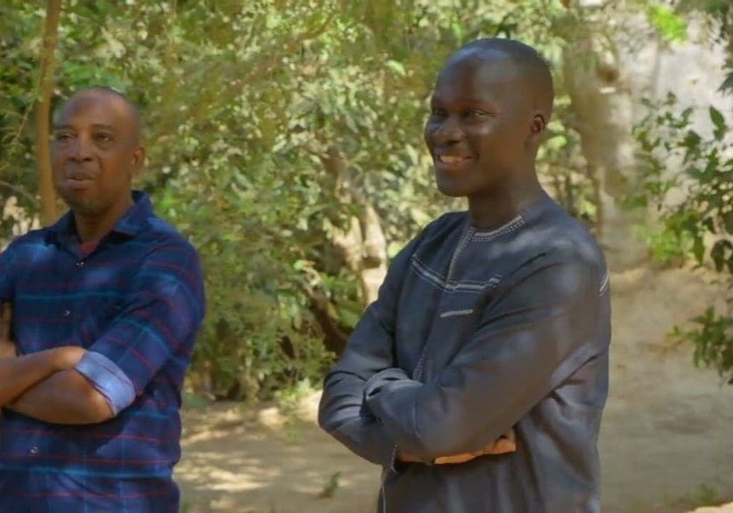 Two men standing outdoors smiling.