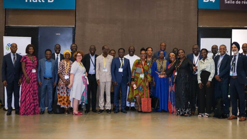 Group of individuals posing for a photo at a conference or event hall.