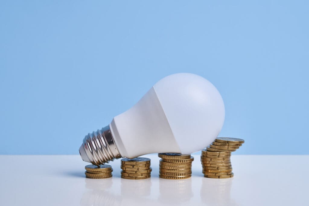 Lightbulb resting on stacks of coins.