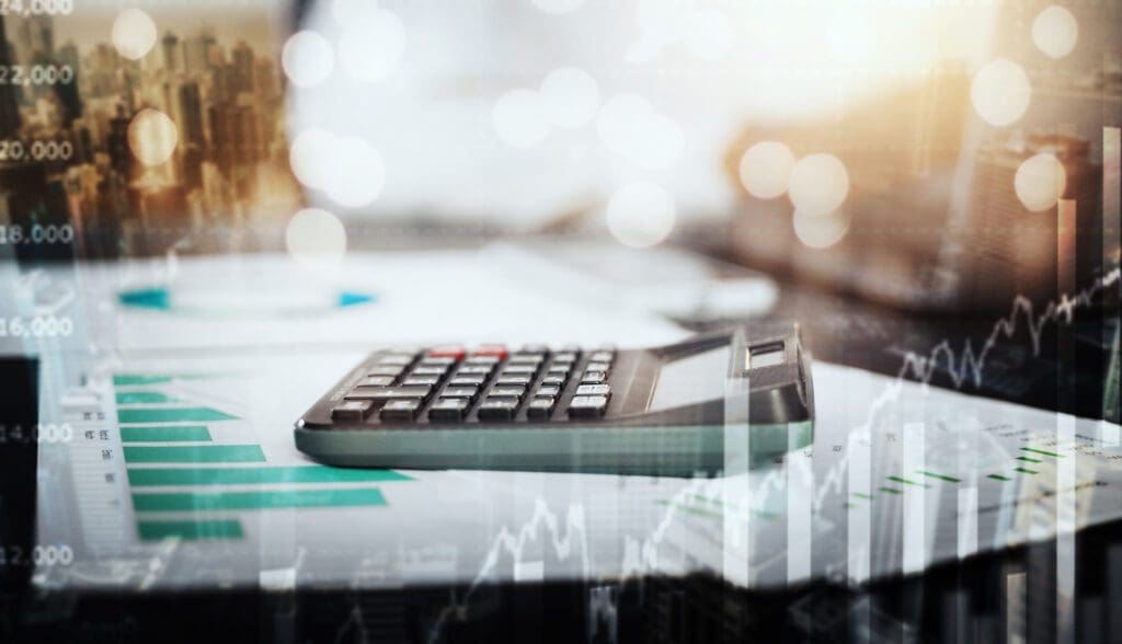 Financial analysis concept with calculator over printed charts and digital graphs overlay.