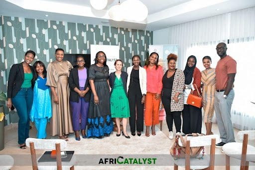 A group of individuals posing for a photo at an indoor event with the logo "africatalyst" in the background.