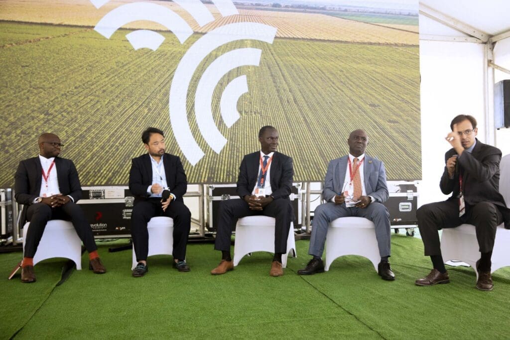 Panelists seated on stage during a conference discussion with an agricultural backdrop.