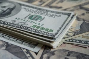 A stack of us dollar bills on a surface.