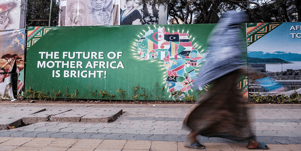 A person walks past a colorful billboard with the message "the future of mother africa is bright!.