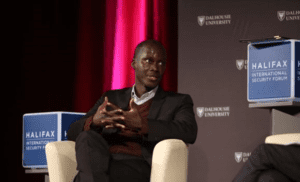 Man speaking at a panel during the halifax international security forum with dalhousie university branding in the background.
