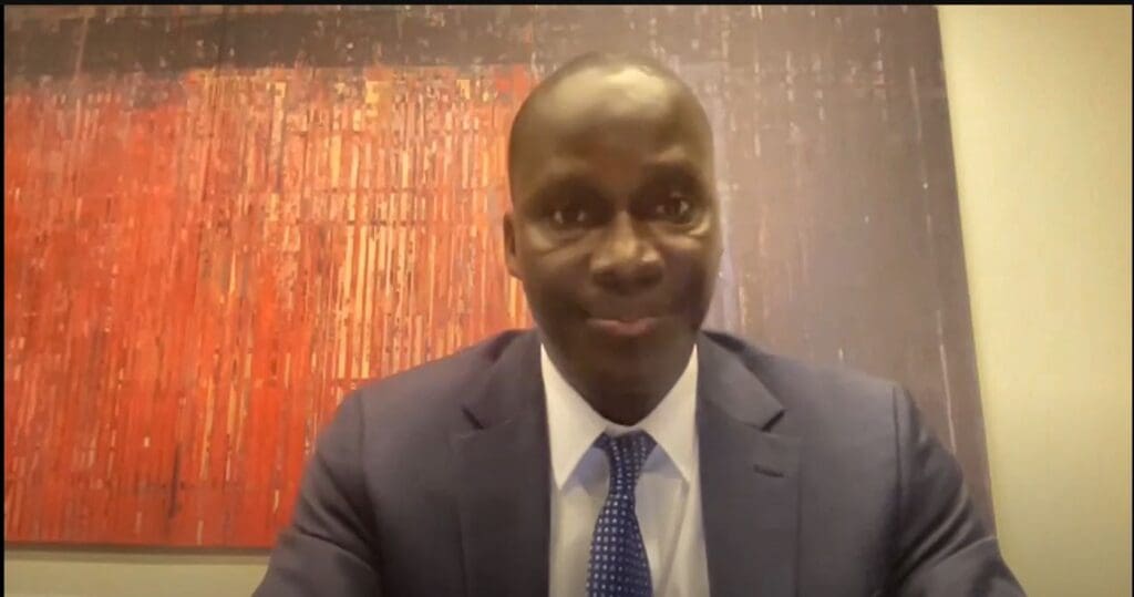 Man in suit smiling, in front of art.