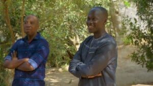 Two men standing outdoors smiling.