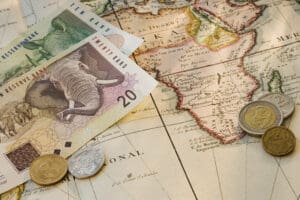 South African rand notes and coins on map