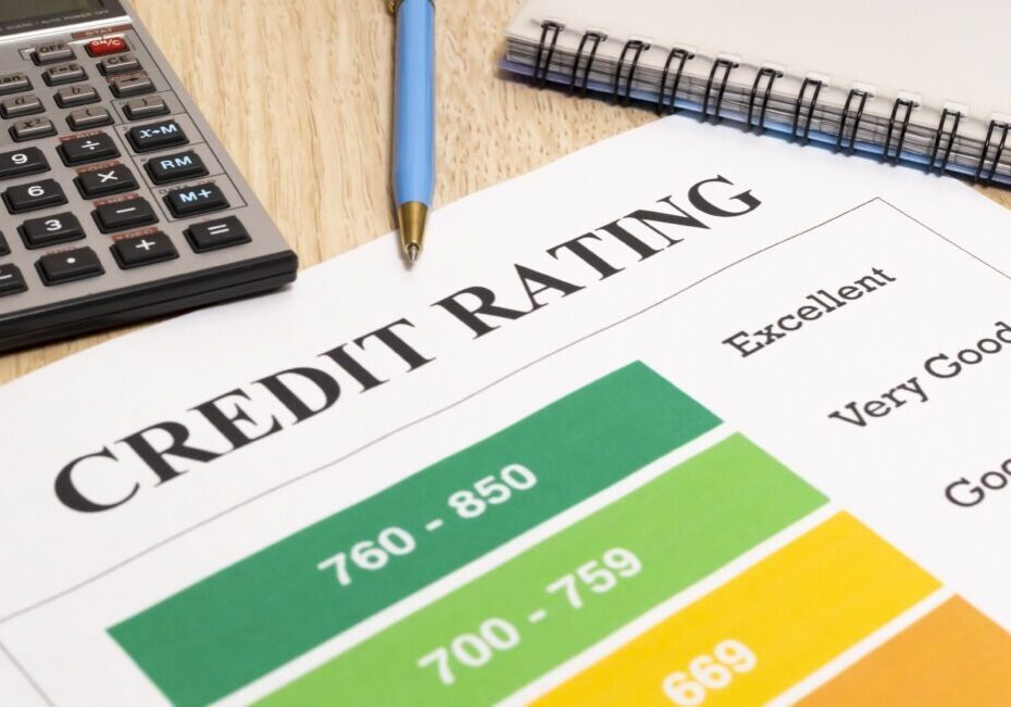 Credit rating chart with score ranges, calculator, and a pen on a wooden desk.
