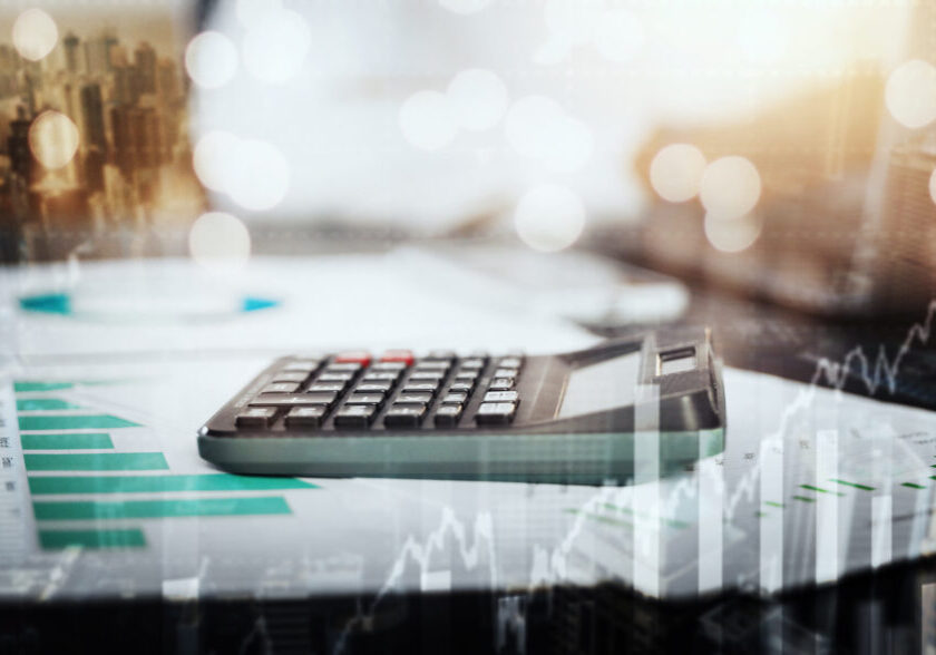 Financial analysis concept with calculator over printed charts and digital graphs overlay.