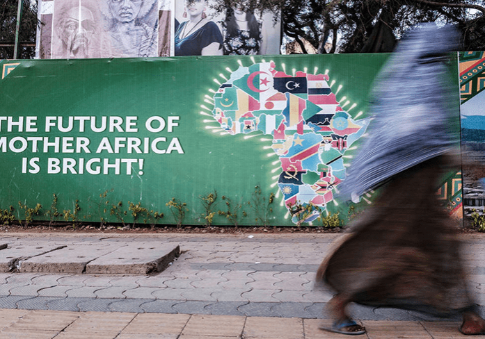 A person walks past a colorful billboard with the message "the future of mother africa is bright!.