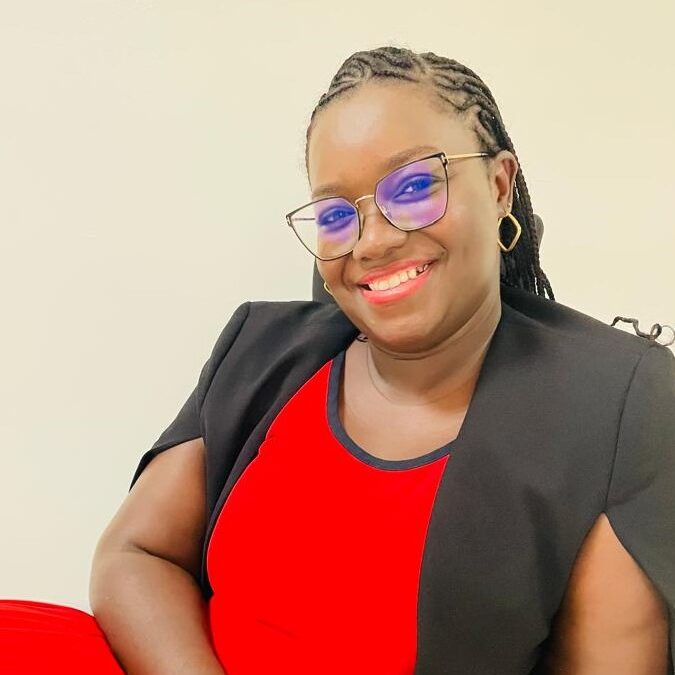 Smiling woman in red dress and glasses.